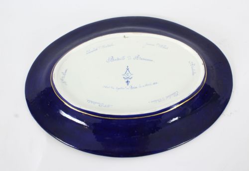 fig 7. An antique French oval porcelain dish featuring a central hand-painted historical battle scene surrounded by a cobalt blue border with gilt lattice work and portrait cartouches.
