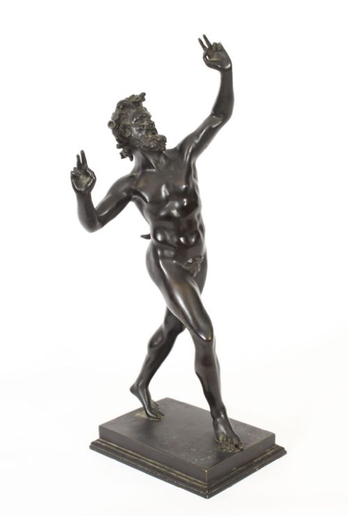 fig 1. A dark patinated bronze figure depicting a dancing faun with raised hands standing on a stepped rectangular base.