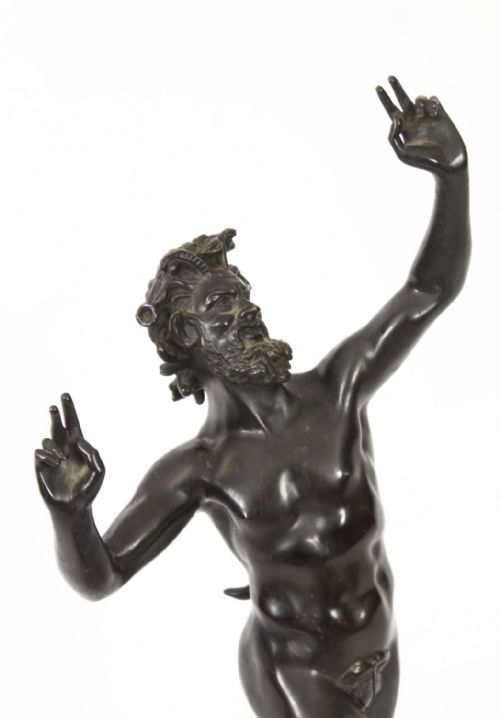 fig 3. A dark patinated bronze figure depicting a dancing faun with raised hands standing on a stepped rectangular base.