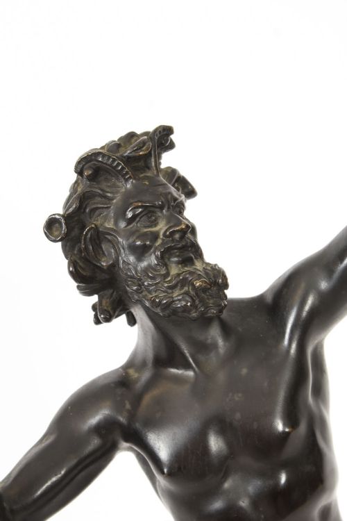 fig 4. A dark patinated bronze figure depicting a dancing faun with raised hands standing on a stepped rectangular base.