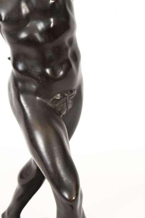 fig 5. A dark patinated bronze figure depicting a dancing faun with raised hands standing on a stepped rectangular base.