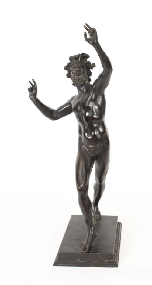 fig 6. A dark patinated bronze figure depicting a dancing faun with raised hands standing on a stepped rectangular base.