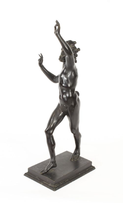fig 7. A dark patinated bronze figure depicting a dancing faun with raised hands standing on a stepped rectangular base.