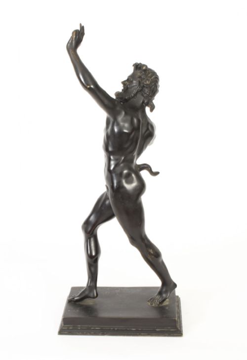 fig 8. A dark patinated bronze figure depicting a dancing faun with raised hands standing on a stepped rectangular base.