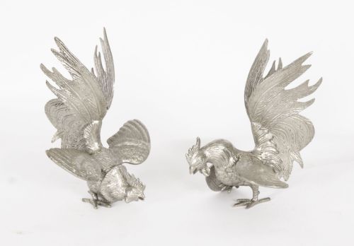 fig 1. A pair of silver-plated fighting cockerels facing each other in dynamic poses with detailed plumage.