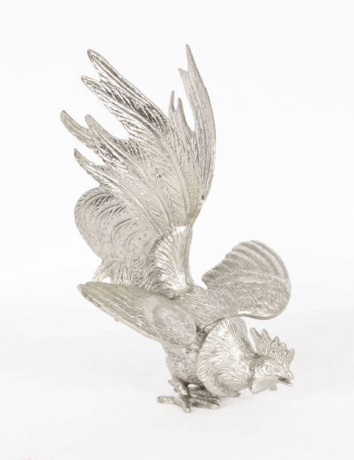 fig 2. A pair of silver-plated fighting cockerels facing each other in dynamic poses with detailed plumage.