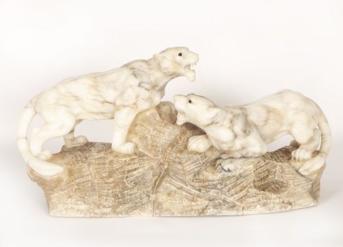 fig 1. An Art Deco carved alabaster sculpture depicting two snarling lionesses positioned atop a rough-hewn stone base.