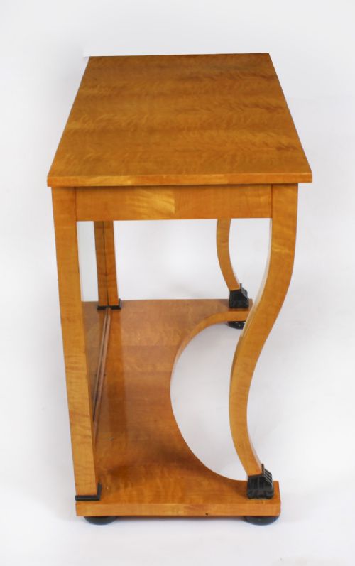 fig 6. A 19th-century Biedermeier console table featuring figured maserbirch veneer, a mirrored back panel, curved front legs with ebonised feet, and a concave lower shelf.