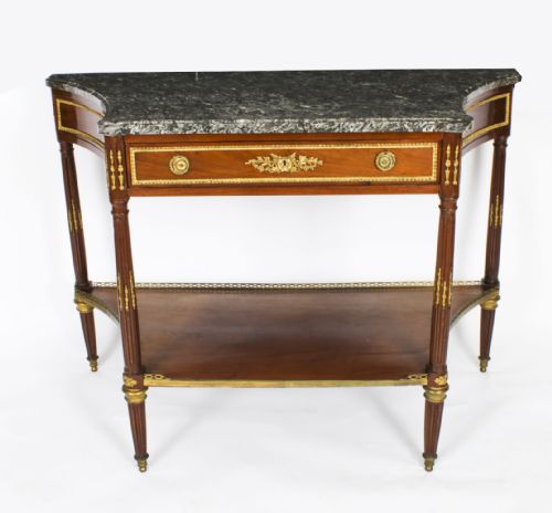 fig 1. An antique French Louis XVI Revival mahogany console table featuring a grey marble top, gilt-bronze mounts, fluted tapered legs, and a lower tier shelf.