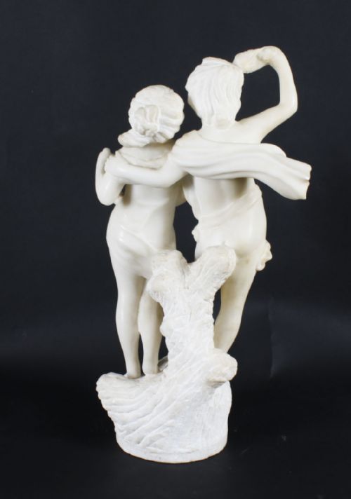 fig 1. A carved off-white marble sculpture featuring two young figures with draped fabric standing on a naturalistic base.