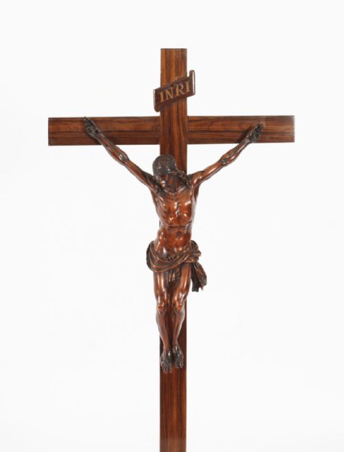 fig 2. A carved wooden Corpus Christi mounted on a dark olive wood cross with an INRI scroll, supported by a tiered hexagonal wooden base.
