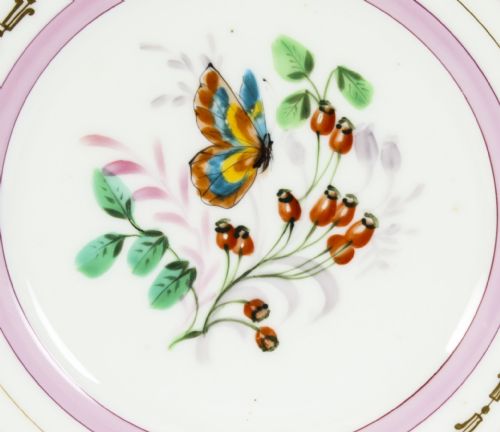 fig 1. An antique French porcelain cabinet plate featuring a scalloped pink border with gilded accents and a central hand-painted motif of a butterfly and wild berries.