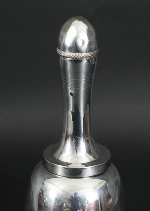 fig 1. A silver-plated Art Deco cocktail shaker shaped like a handbell with a polished metal finish.