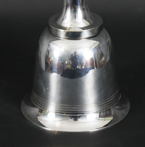 fig 3. A silver-plated Art Deco cocktail shaker shaped like a handbell with a polished metal finish.