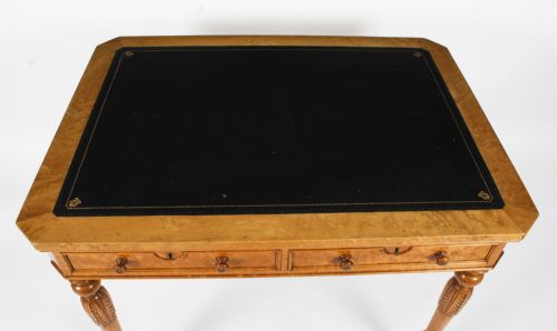 fig 2. A late 19th-century birdseye maple writing table featuring a black leather inset top, two front frieze drawers, and turned carved legs on brass castors.