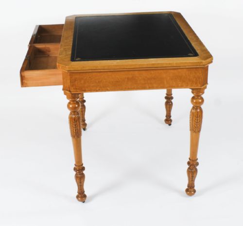 fig 3. A late 19th-century birdseye maple writing table featuring a black leather inset top, two front frieze drawers, and turned carved legs on brass castors.