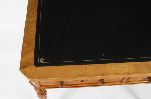 fig 4. A late 19th-century birdseye maple writing table featuring a black leather inset top, two front frieze drawers, and turned carved legs on brass castors.