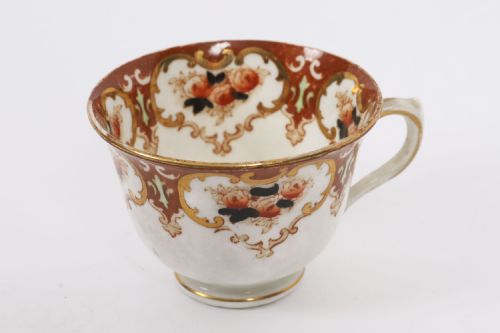 fig 2. An antique twenty-one piece bone china tea set featuring white porcelain decorated with elaborate brown and gilded floral border patterns.