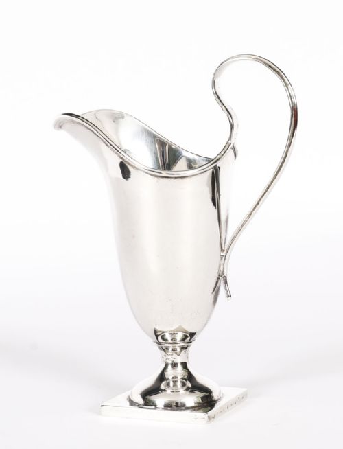 fig 1. A solid sterling silver cream jug featuring a high loop handle, flared spout, and a square pedestal base.