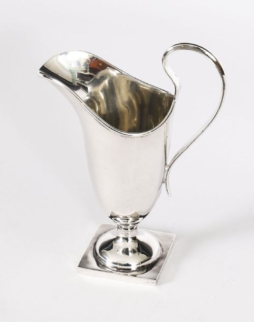 fig 2. A solid sterling silver cream jug featuring a high loop handle, flared spout, and a square pedestal base.