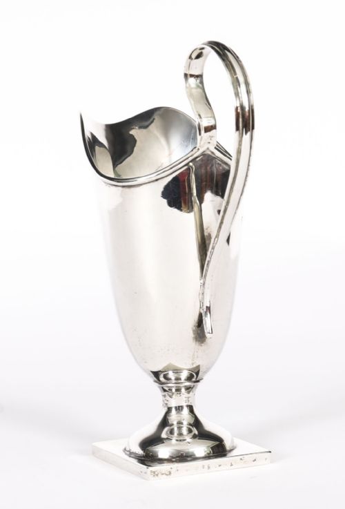 fig 3. A solid sterling silver cream jug featuring a high loop handle, flared spout, and a square pedestal base.