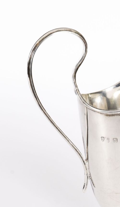 fig 4. A solid sterling silver cream jug featuring a high loop handle, flared spout, and a square pedestal base.