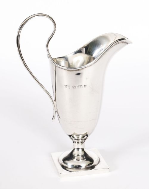 fig 5. A solid sterling silver cream jug featuring a high loop handle, flared spout, and a square pedestal base.