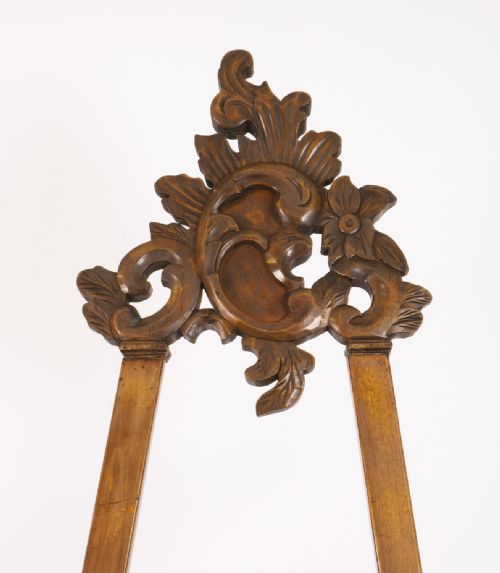 fig 3. An antique carved walnut artist easel featuring an ornate Rococo cresting, an adjustable shelf, and scrolled leg supports.