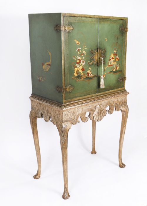 fig 2. A green lacquered two-door cocktail cabinet with hand-painted chinoiserie scenes resting on a carved silver gilt stand with cabriole legs.