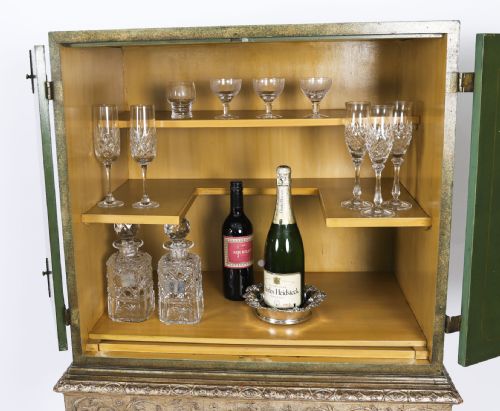 fig 4. A green lacquered two-door cocktail cabinet with hand-painted chinoiserie scenes resting on a carved silver gilt stand with cabriole legs.