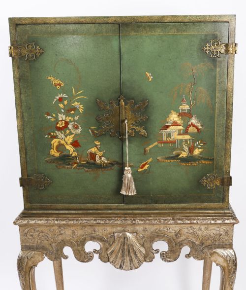 fig 5. A green lacquered two-door cocktail cabinet with hand-painted chinoiserie scenes resting on a carved silver gilt stand with cabriole legs.