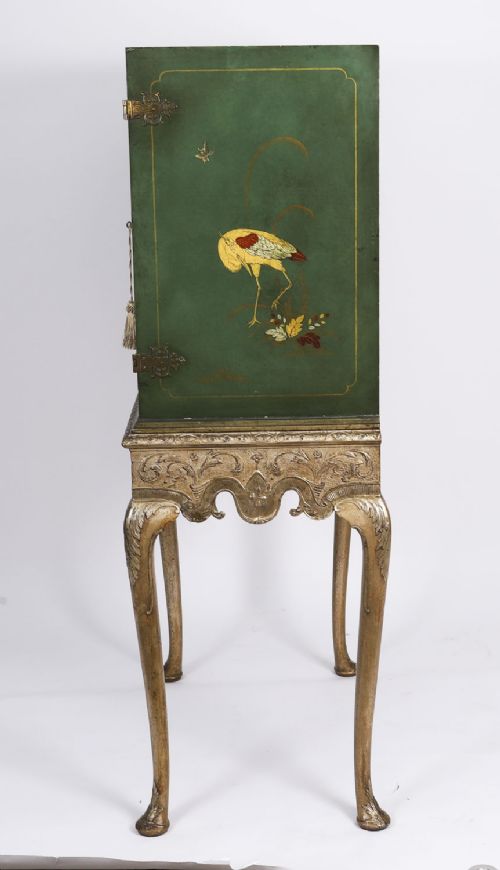 fig 8. A green lacquered two-door cocktail cabinet with hand-painted chinoiserie scenes resting on a carved silver gilt stand with cabriole legs.