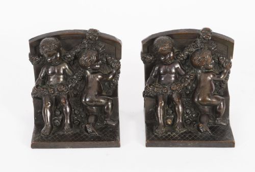 fig 2. A pair of dark brown patinated bronze bookends depicting seated classical cherubs holding floral garlands on stepped bases.