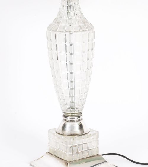fig 2. An Art Deco table lamp featuring a faceted clear cut crystal stem, a square metal pedestal base, and a cream pleated fabric lampshade.