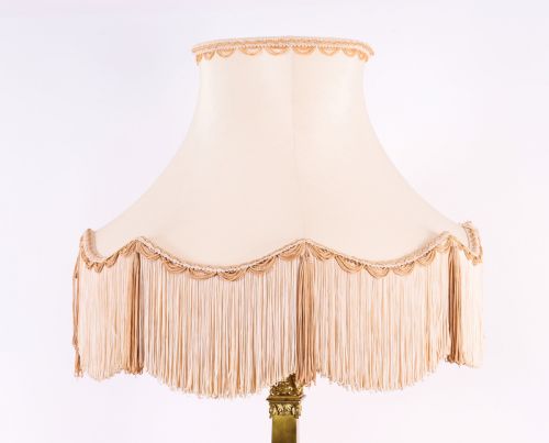fig 4. A pair of 19th-century French ormolu table lamps featuring cast gilt bronze bases and cream flared fabric shades with tassel fringe trim.