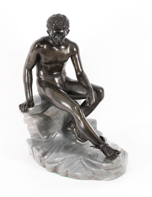 fig 1. A dark patinated bronze sculpture depicting a nude seated Hermes resting on a carved grey marble base.