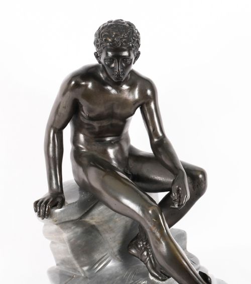 fig 2. A dark patinated bronze sculpture depicting a nude seated Hermes resting on a carved grey marble base.