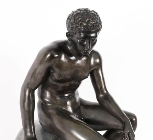 fig 3. A dark patinated bronze sculpture depicting a nude seated Hermes resting on a carved grey marble base.
