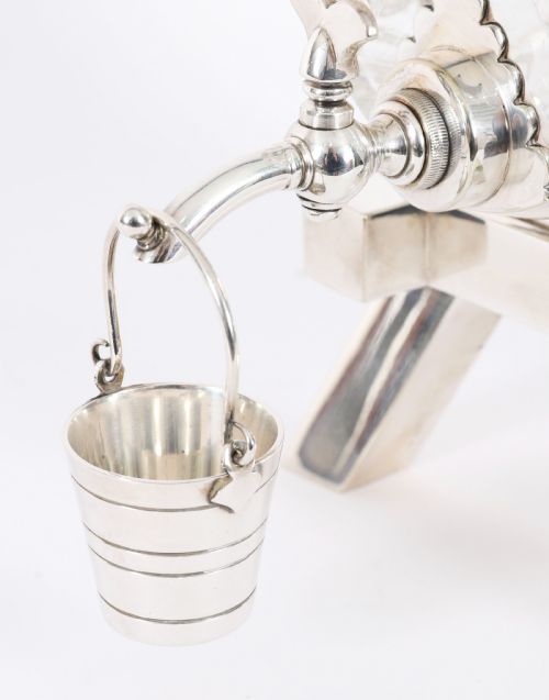 fig 1. A nineteenth-century cut crystal barrel decanter with silver-plated hoops, tap, and miniature bucket accessory resting on a four-legged silver stand.