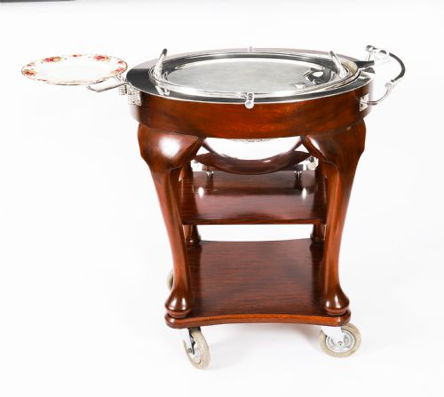 fig 3. An Art Deco silver-plated beef carving trolley with a hemispherical revolving dome cover mounted on a dark mahogany frame with cabriole legs.