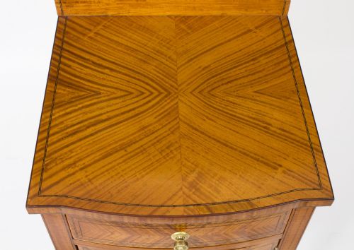 fig 2. A Victorian satinwood bedside cabinet featuring a bowfront shape, chevron veneer patterns, a single drawer, a cupboard door, and tapered square legs.