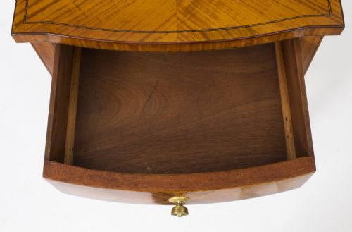fig 4. A Victorian satinwood bedside cabinet featuring a bowfront shape, chevron veneer patterns, a single drawer, a cupboard door, and tapered square legs.