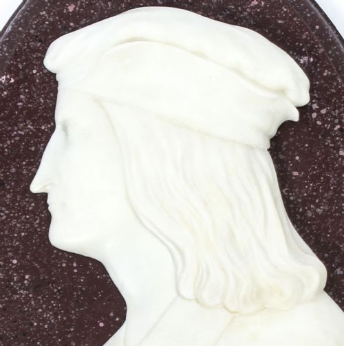 fig 3. A pair of 19th-century oval plaques featuring white carved marble profile busts of Dante and Virgil set against dark mottled stone backgrounds.