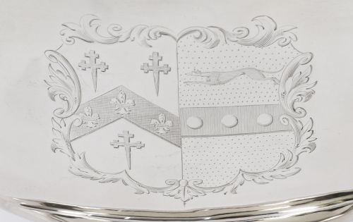 fig 3. A George III sterling silver tureen with two looped handles, a domed lid, a pedestal base, and an engraved heraldic crest.