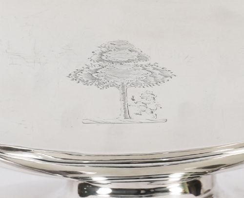 fig 6. A George III sterling silver tureen with two looped handles, a domed lid, a pedestal base, and an engraved heraldic crest.
