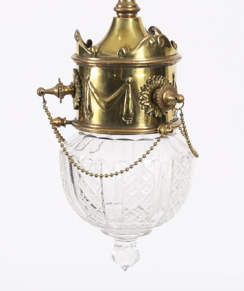 fig 1. An Edwardian ceiling pendant light featuring an ornate brass gallery decorated with swags and rosettes, suspending a cut crystal glass globe with a pointed base finial.