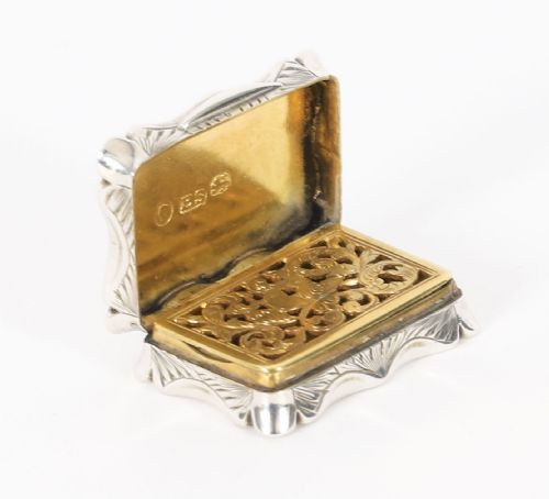 fig 4. An open Victorian sterling silver vinaigrette displaying a scalloped edge and a hinged floral pierced gilt interior grille.