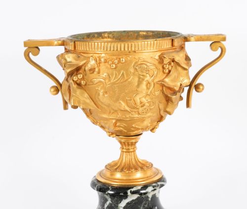 fig 2. A pair of nineteenth-century French gilt bronze classical urns featuring relief carvings and scroll handles, mounted on dark green marble bases.