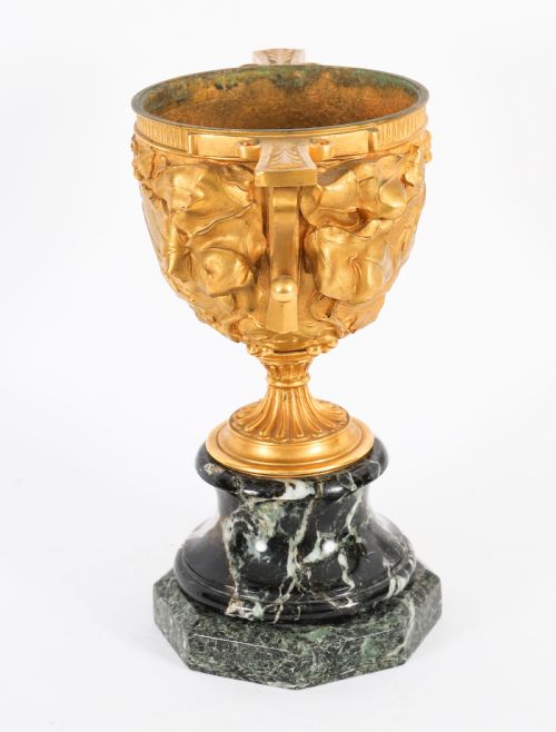 fig 5. A pair of nineteenth-century French gilt bronze classical urns featuring relief carvings and scroll handles, mounted on dark green marble bases.