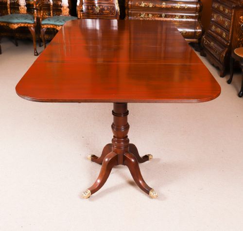 fig 3. A George III Regency period mahogany twin pillar dining table featuring reeded edge detail and tripod pedestal legs with brass castors.